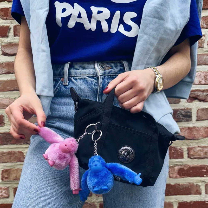 A woman with a black Kipling handbag with two monkey keychains