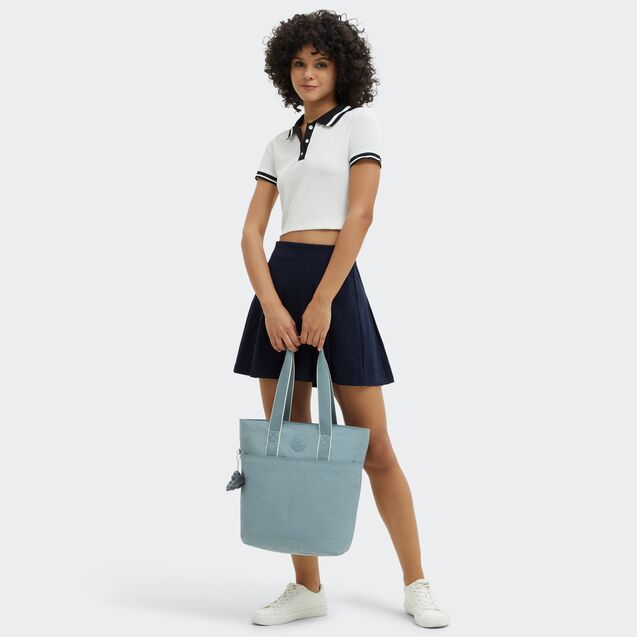 Woman holding a light grey Kipling tote bag against a white background