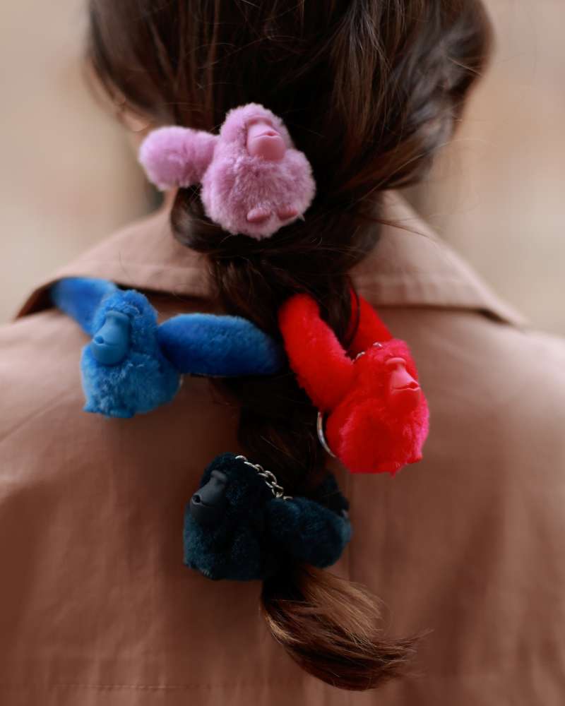 Four colorful monkey keychains hanging on woman's hair. 